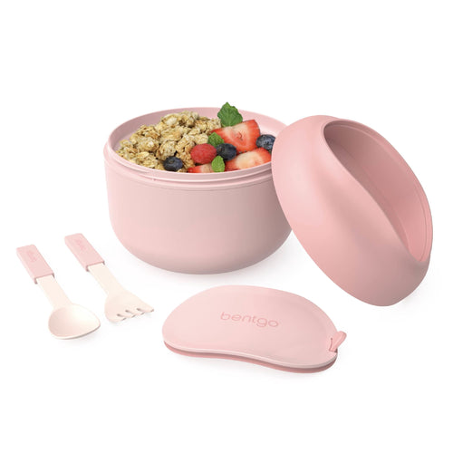 Blush pink insulated bowl with lid, collapsible spoon and fork, and cereal topped with berries on white background.