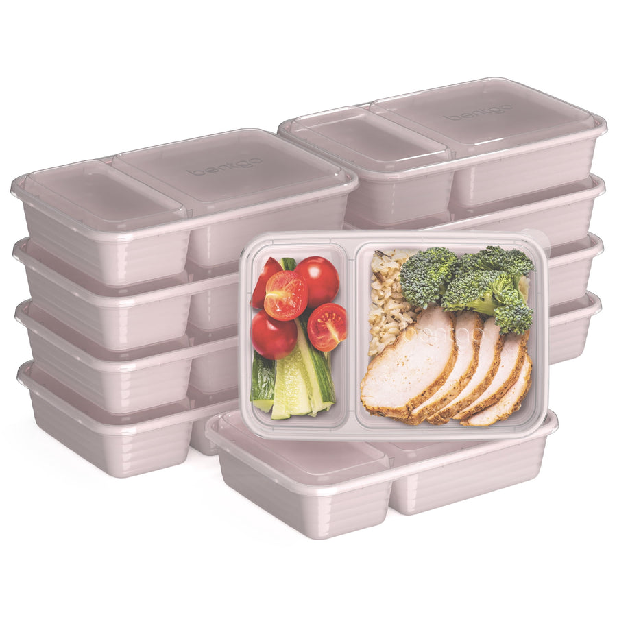 Stack of blush pink two-compartment meal prep containers with clear lids and one filled sample container showing food.