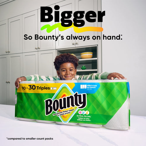 Child leaning on a large packaged Bounty paper towels multipack in a bright kitchen with 'Bigger' headline above