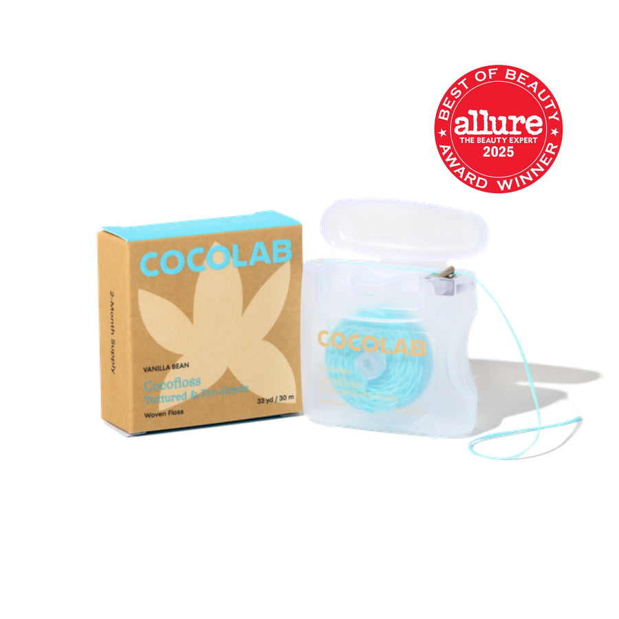 Cocofloss refillable dental floss in translucent case with turquoise floss next to kraft vanilla bean box and award badge