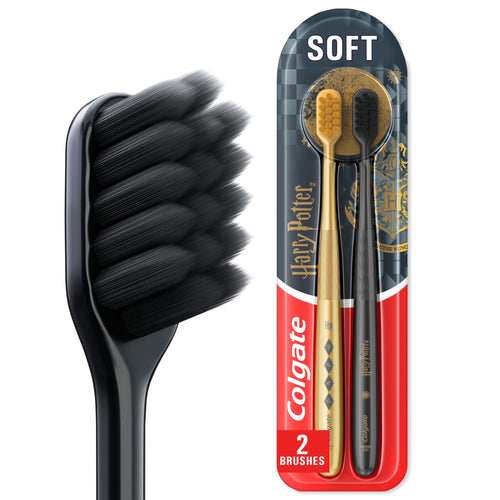 Close-up of a black soft-bristled toothbrush head beside packaged Colgate Harry Potter two-pack with gold and black handles