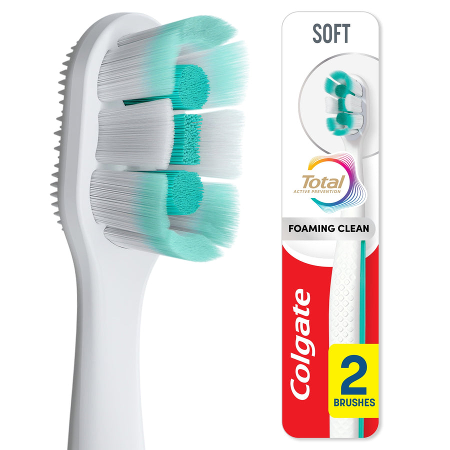 Close-up of a white Colgate toothbrush head with teal center pads alongside its branded packaging card labeled 'Soft' and '2 brushes'.