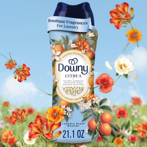 Close-up of a Downy Citrea Boutique Botanicals scent booster bottle with floral artwork and citrus accents against a sky background.