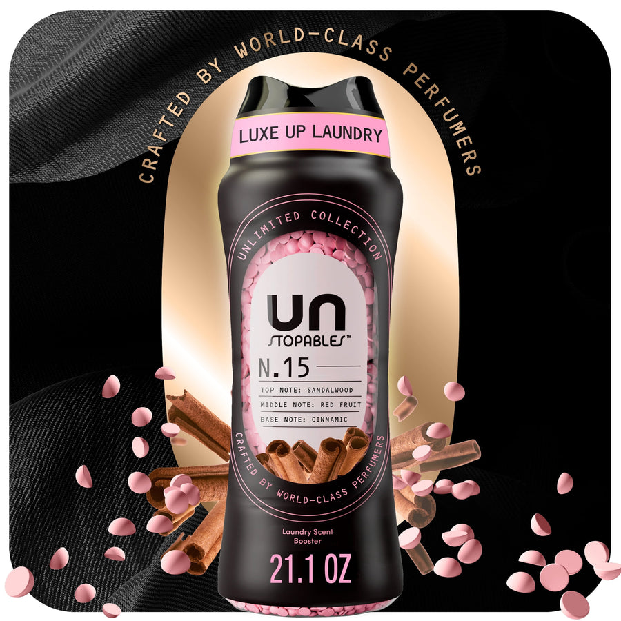 Black bottle of Downy Unstopables N.15 scent beads with pink beads and cinnamon accents on a dark background