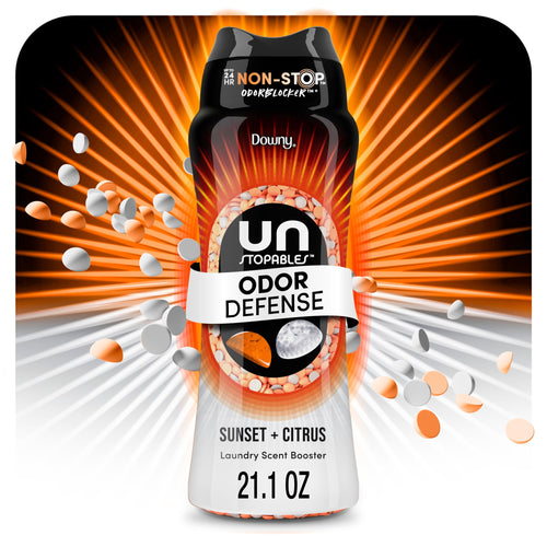 Close-up stylized bottle of Downy Unstopables Odor Defense Sunset + Citrus with orange and white scent beads bursting outward