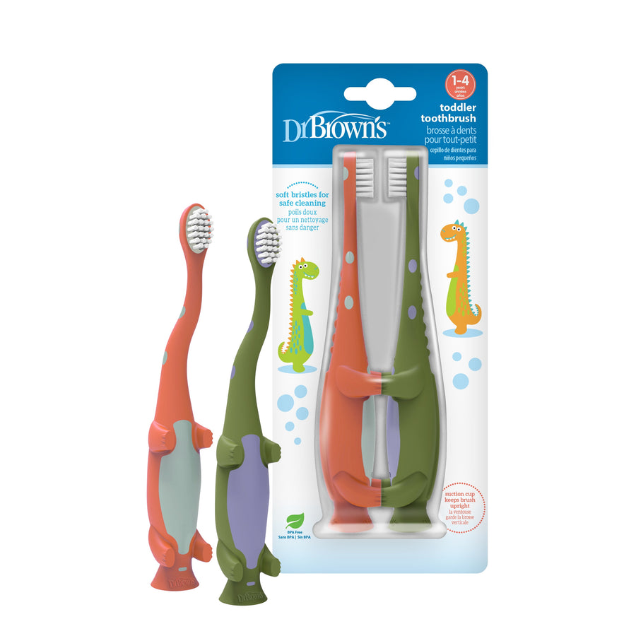 Packaged Dr. Brown's toddler toothbrush duo with green and orange dinosaur-themed handles in blister pack.