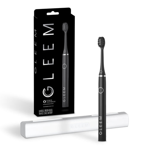 Black Gleem battery-powered toothbrush upright with white travel case and retail box on white background.