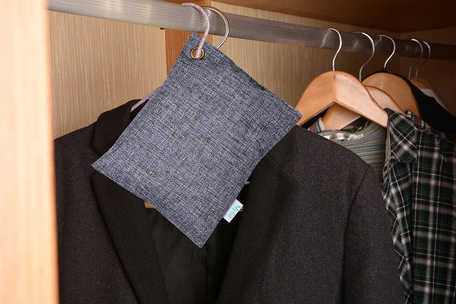 Gray textured fabric air-purifying pouch hanging on a closet rod among jackets