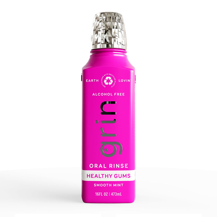 Tall magenta Grin oral rinse bottle with silver textured cap on white background.