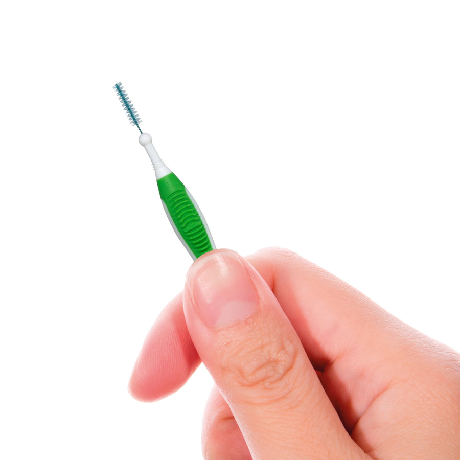 Close-up of a hand holding a green-handled GUM interdental brush showing the small cylindrical bristle head