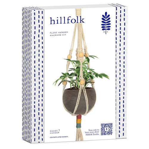 Hillfolk branded retail box showing a macrame plant hanger with wooden beads and a potted plant on white background.