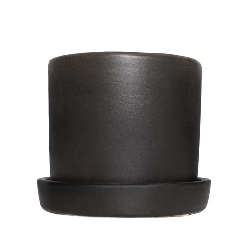 Matte black cylindrical ceramic planter with matching saucer on a white background