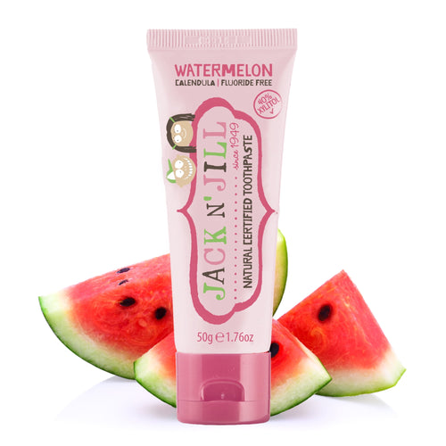 Pink Jack N' Jill watermelon toothpaste tube standing in front of sliced watermelon pieces on white background