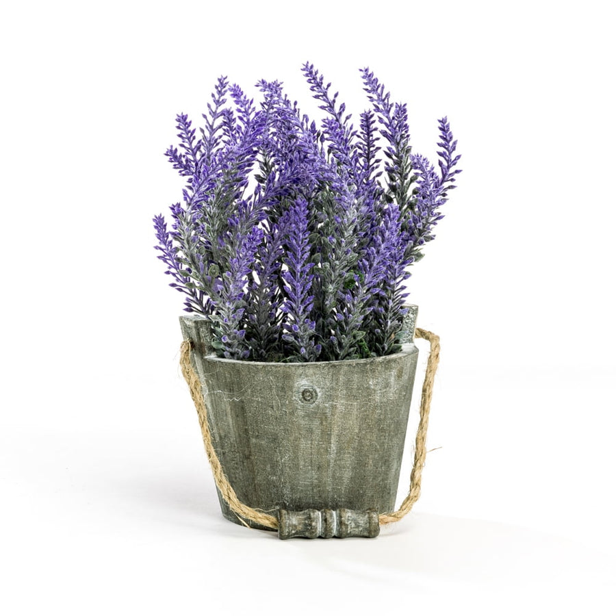 Potted artificial lavender stems arranged in a rustic gray wooden bucket planter with rope handle on white background.