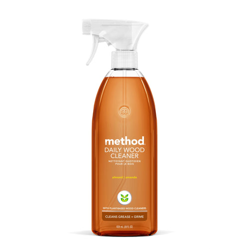 Clear amber spray bottle of Method Daily Wood Cleaner with white trigger and almond labeling on a white background