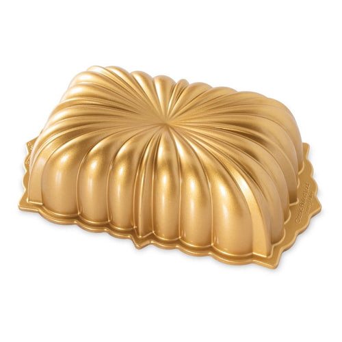 Gold-colored fluted loaf pan turned upside down showing decorative shell-like ridged exterior