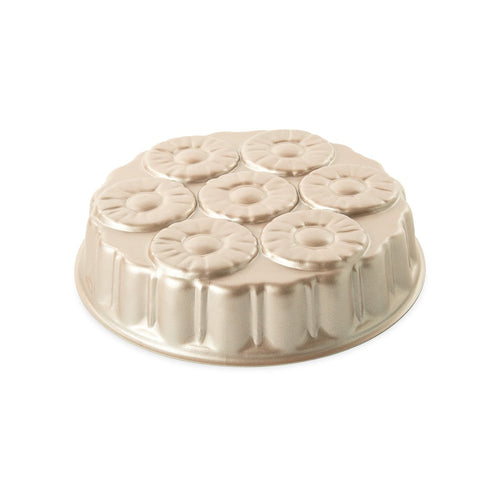 Gold-toned metal cake pan with seven pineapple-style ring molds arranged in a circular pattern