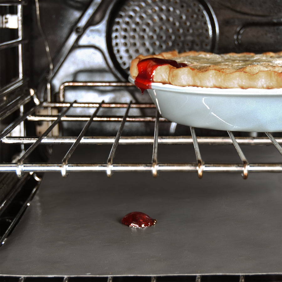 Oven interior with a pie on the rack and a Range Kleen oven liner catching a drip on the oven floor.
