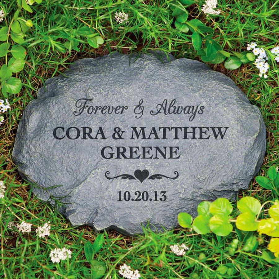 Engraved garden stone reading "Forever & Always" with names Cora & Matthew Greene and date 10.20.13, set in grass and small flowers.
