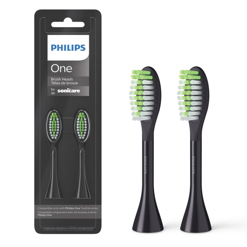 Two black Philips One by Sonicare replacement brush heads shown beside their black blister package with visible branding.