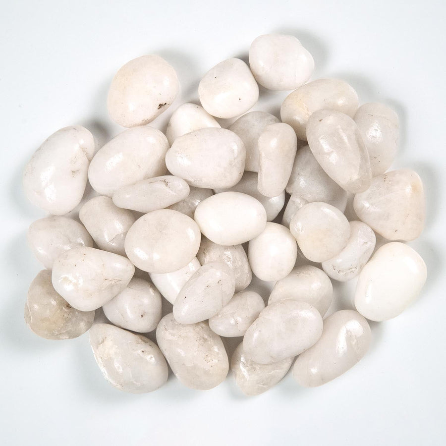 Top-down view of a loose pile of glossy white polished pebbles on a light background