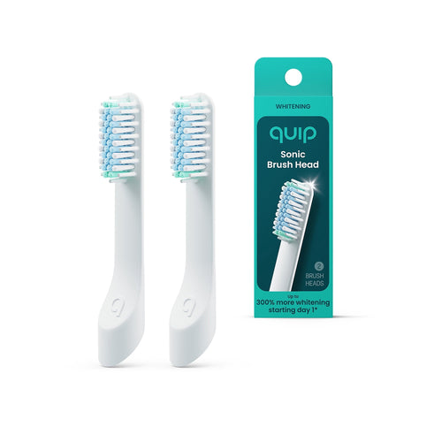 Two white quip sonic replacement brush heads standing beside teal quip retail box showing one brush head image