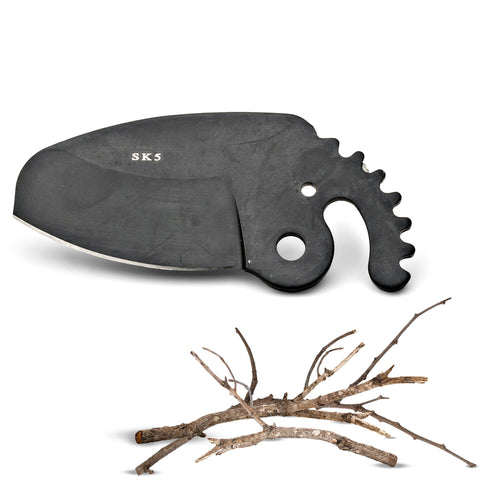 Close-up of a black SK5 anvil-style replacement blade resting above small dry branches