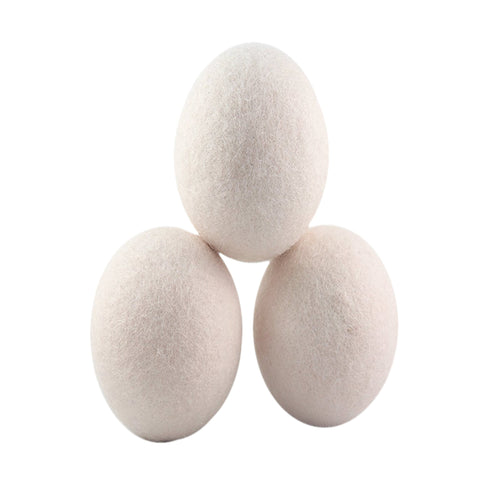 Three natural white wool dryer balls stacked in a pyramid on a white background