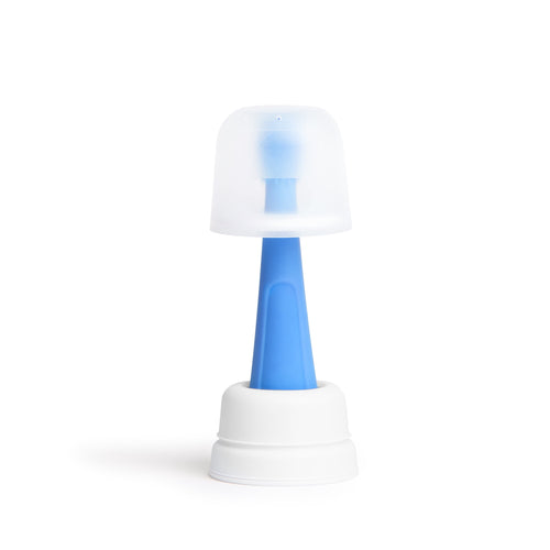 Blue silicone infant training toothbrush with white safety guard and translucent protective cap, displayed upright on a white base.