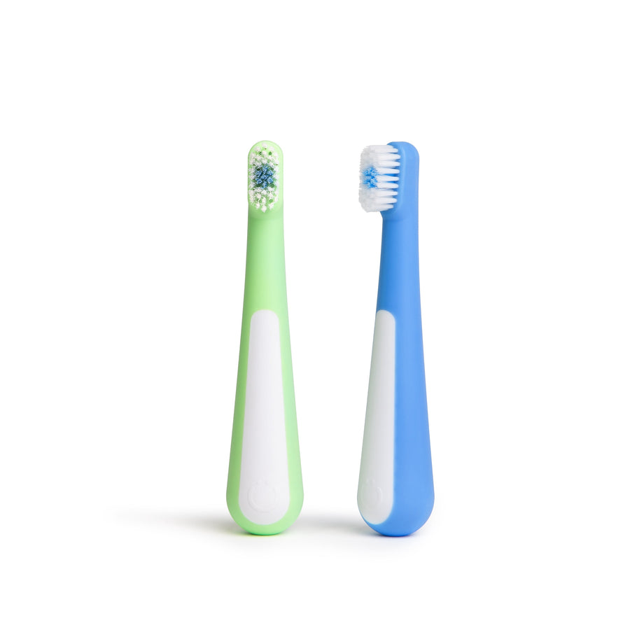 Two toddler toothbrush heads and ergonomic handles in green and blue on a white background.