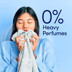 Person holding a fabric to their face with large text '0% Heavy Perfumes' and Downy Light branding on a pale blue background