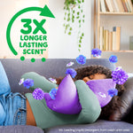 Person sleeping on a couch hugging a purple pillow with floating flowers and a green badge reading '3X LONGER LASTING SCENT'