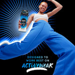Person in blue pants jumping while holding a Downy Unstopables Odor Defense bottle with 'designed to work best on activewear' text