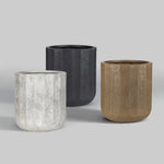 Three fluted resin planters in charcoal, whitewashed, and warm brown finishes displayed on gray background