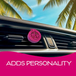 Pink circular air freshener clipped to a car air vent with palm trees and blue sky visible outside the window