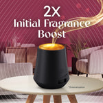 Promotional image showing an Air Wick diffuser on a table with text "2x Initial Fragrance Boost" and stylized scent trail