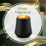 Black Air Wick Essential Mist diffuser on a table with stylized fragrance smoke and 'Enjoy Fragrance' text