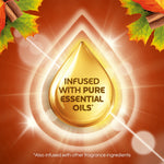 Gold oil drop graphic with text "Infused with pure essential oils" on autumn-themed background with leaves and spices