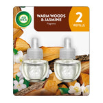 Two Air Wick plug-in scented oil refill bottles on a warm woods and jasmine package background.