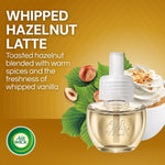 Closeup promo graphic of a single Air Wick Whipped Hazelnut Latte refill bottle with hazelnuts and whipped vanilla dessert imagery