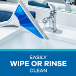 AirBroom head being rinsed under a bathroom faucet over a sink, showing blue silicone blade and water flow