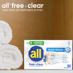 All free·clear dryer sheets box staged on a shelf next to rolled white towels in warm setting