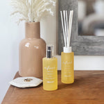 Styled duo of Allswell products including a frosted 'refresh' spray bottle and matching reed diffuser on a wooden surface