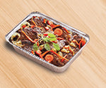 Aluminum rectangular pan on wood surface filled with roasted meat and vegetables