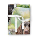 Folded apron showing a close-up of a brown spaniel's face and white apron ties on top