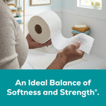 Hands holding an Angel Soft toilet paper roll and an embossed sheet in a bathroom; teal slogan banner below