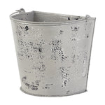 Angled view of a distressed farmhouse-style metal bucket planter with visible worn paint texture