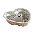 Angled view of a floral heart bundt pan showing the interior embossed rose details and the heart-shaped central tube.
