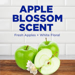 Graphic reading "APPLE BLOSSOM SCENT" with fresh green apples and a white flower on a wooden surface and tiled background.