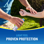 Close-up of an adult spraying a Cutter All Family can onto a child's forearm in a backyard scene.